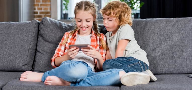 tablets e smartphones para criancas irmaos no sofa a jogar